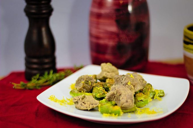 Ein Teller mit Lammfleisch auf grünem Spargel, garniert mit geriebener Zitronenschale