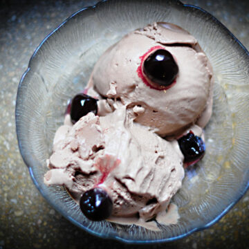 Eine Schale mit zwei Kugeln Schokoladeneis, garniert mit Amarenakirschen