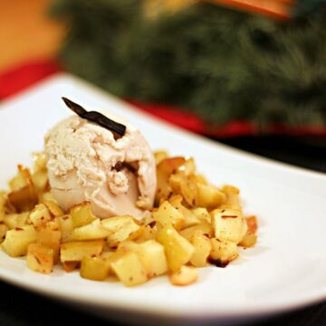 Ein Dessertteller mit Bratapfelkompott mit einer Kugel Haselnusseis in der Mitte