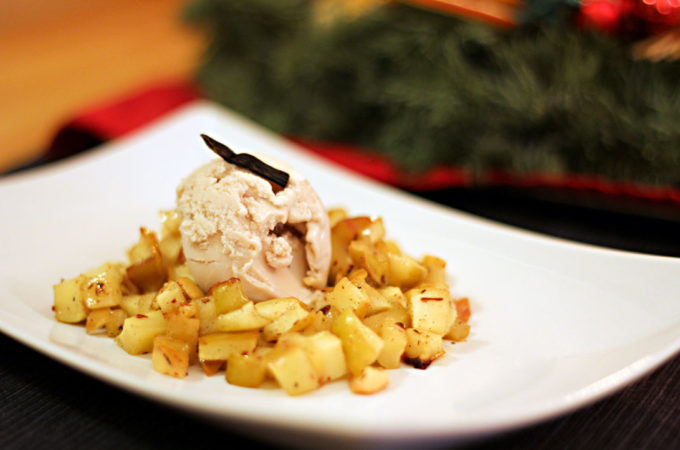 Ein Dessertteller mit Bratapfelkompott mit einer Kugel Haselnusseis in der Mitte