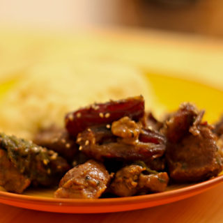 Abbildung eines Tellers, auf dem geschmortes Lammfleisch mit Datteln und Walnüssen sowie Couscous liegt.