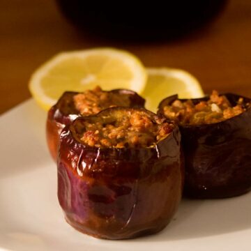 Drei kleine Auberginen, die mit Hackfleisch gefüllt sind.