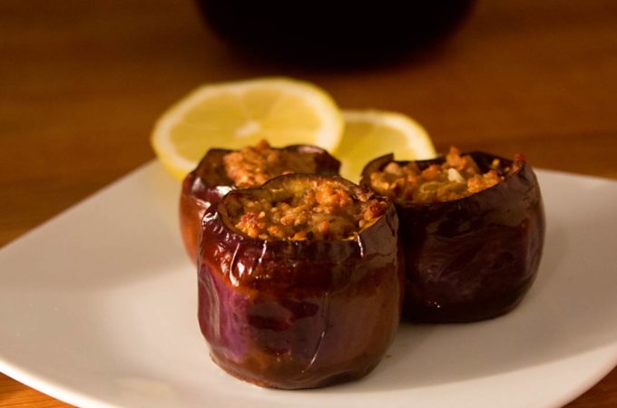 Drei kleine Auberginen, die mit Hackfleisch gefüllt sind.