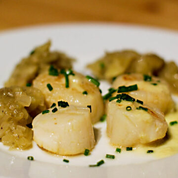 Vier gebratene Jakobsmuscheln und Auberginenmus auf einem Teller