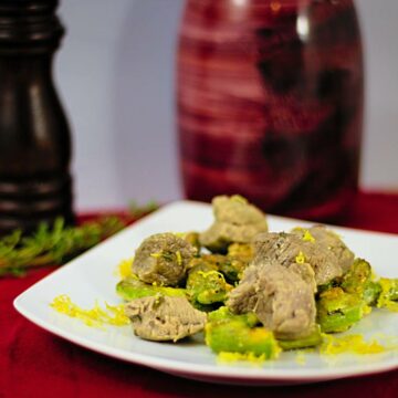 Ein Teller mit Lammfleisch auf grünem Spargel, garniert mit geriebener Zitronenschale