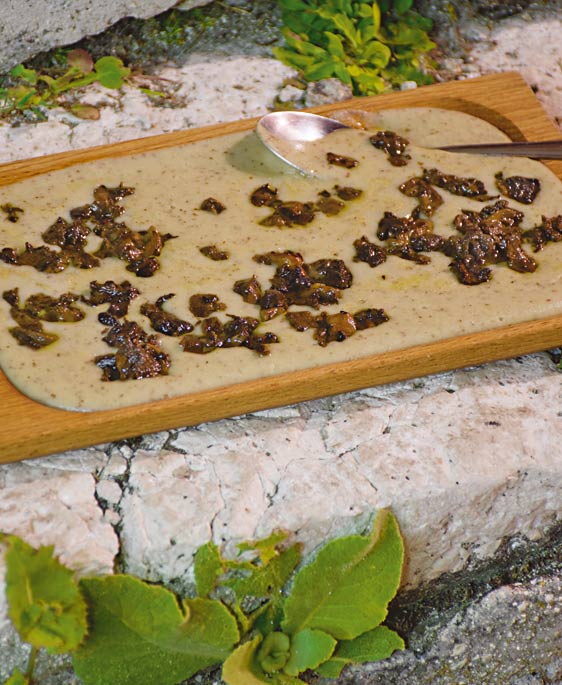 Auf einem Holzbrett wird der umbrische Wilderbsenbrei Farrecchiata serviert.