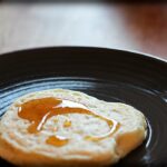 Ein marokkanischer Pfannkuchen mit Honigsirup auf einem braunen Teller.