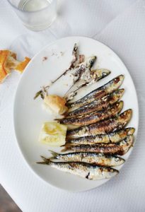 Ein weißer Teller mit gegrillten Sardinen a la plancha