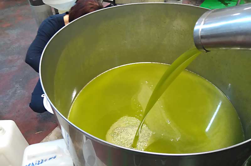 Ein großes Gefäß, in das frisches Olivenöl fließt.