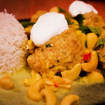 Nahaufnahme von Hackfleischbällchen mit Cashews und Joghurt, mit Reis angerichtet.