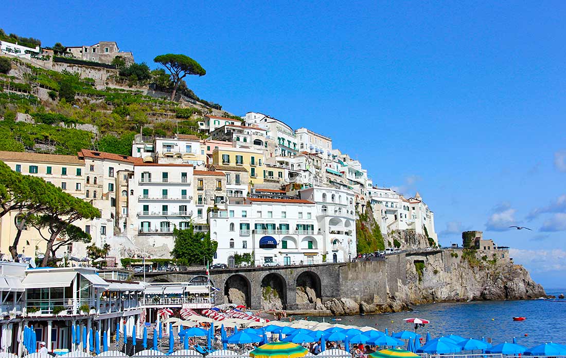 Eng gebaute Häuser an einem Steilhang von Amalfi, darunter das Meer.