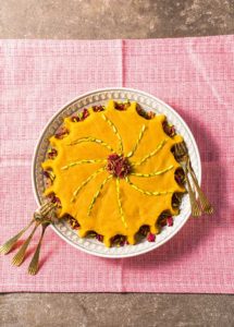 Auf einer rosa Decke steht eine Schüssel mit der Süßspeise Halva, mit Pistazien dekoriert.