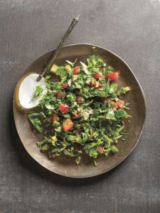Auf einem Kupferteller ist ein Salat aus Kräutern angerichtet.