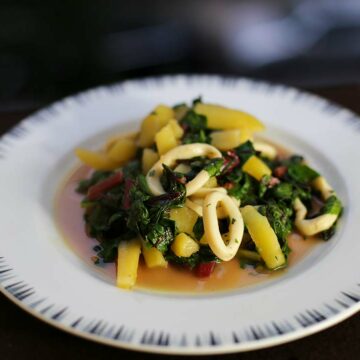 Ein Teller mit Tintenfischringen an Kartoffeln und Mangold