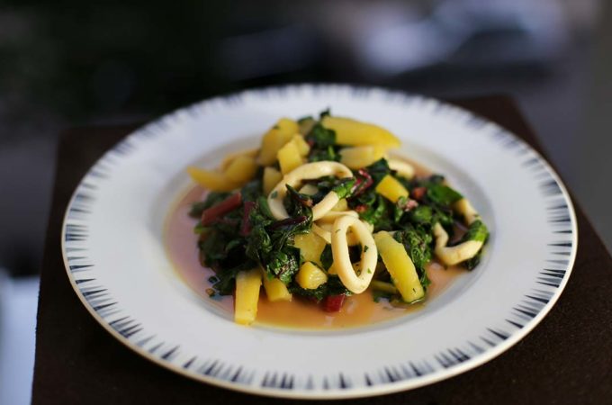 Ein Teller mit Tintenfischringen an Kartoffeln und Mangold