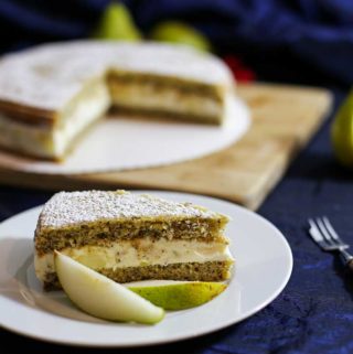 Ein Stück Ricotta-Birnen-Torte auf einem Teller, garniert mit zwei Birnenspalten. Im Hintergrund der Rest der Torte.