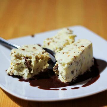 Ein Dessertteller mit zwei Stückchen Haselnuss-Semifreddo mit Schokoladensauce.