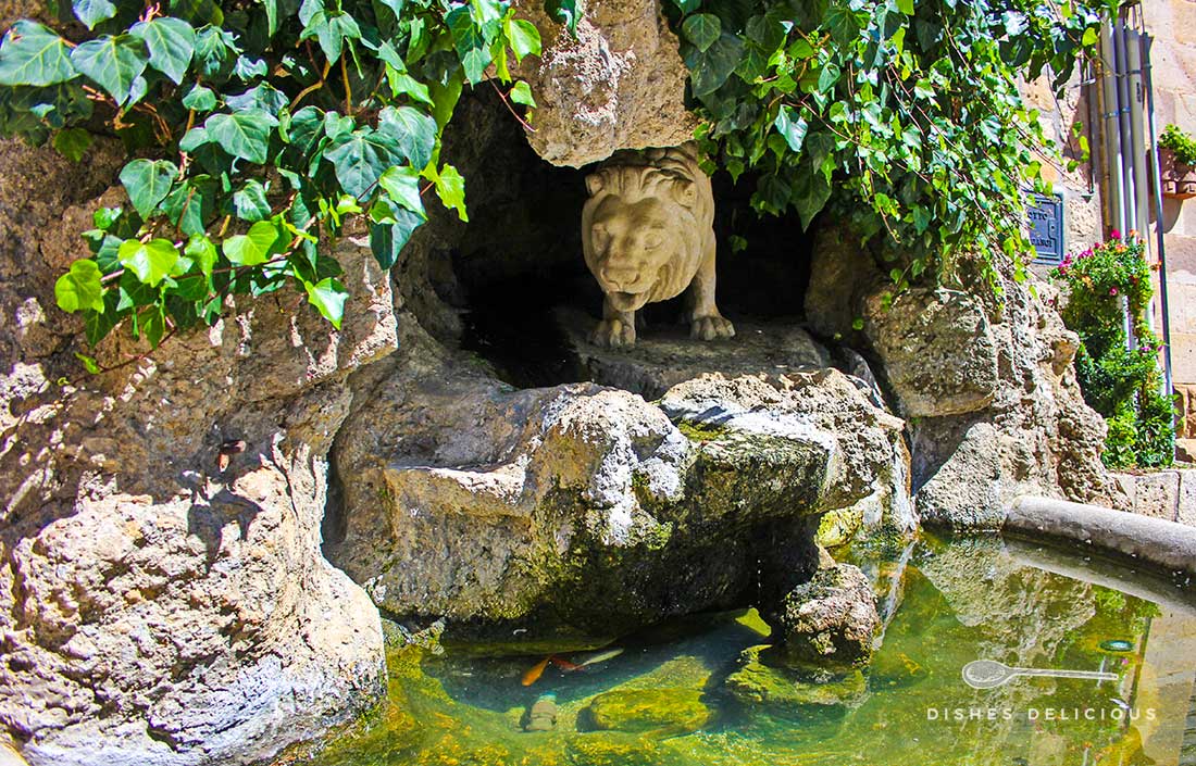 Brunnen in Gangi - er zeigt einen Mamorlöwen der aus einer Höhle ans Wasser schleicht.