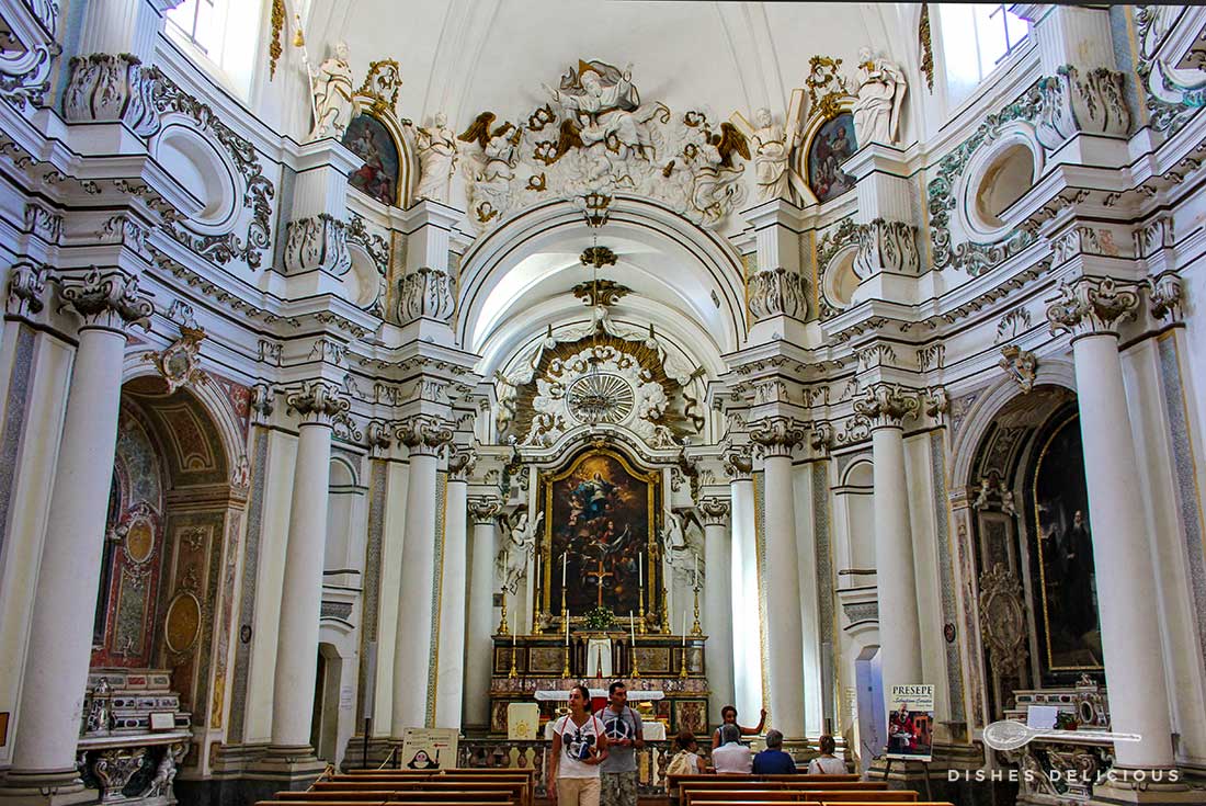 Das Innere der Santa Chiara-Kirche: stuckverzierte Säulen und viele Heiligenfiguren.