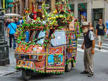 Eine bunt geschmückte Ape und Blumen und ihr betagter Besitzer an den Quattro Canti in Palermo.