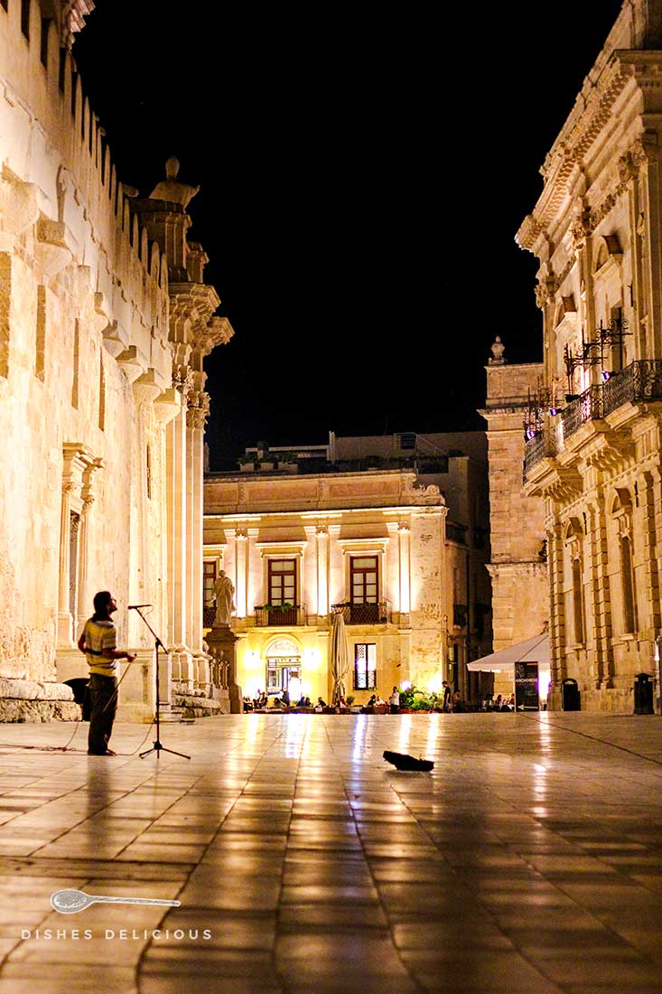 Ein Straßenmusiker singt abends auf der menschenleeren Piazza Minerva in Syrakus.