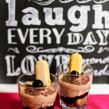 Zwei Dessertgläser mit Schoko-Tiramisu, garniert mit Amarenakirschen und Löffelbiskuits.