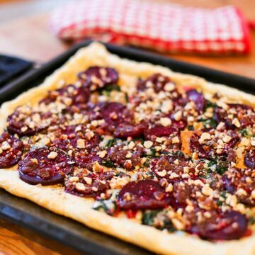 Eine Tarte mit Rote Bete, bestreut mit gehackten Haselnüssen, auf einem Backblech