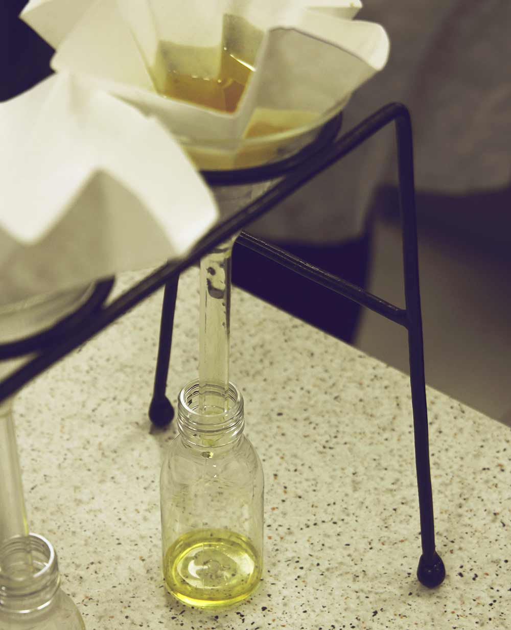 Olivenöl-Herstellung im Labor: das fertige Öl wird durch einen Filter in eine Flasche gefüllt