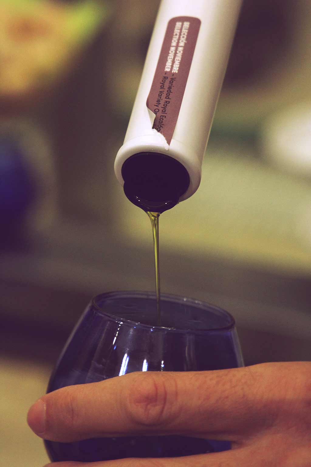 Olivenöl wird aus einer Flasche in ein blaues Glas gegossen