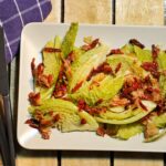 Geschmorter Wirsing auf einem eckigen Teller, garniert mit Pancetta und Tomate