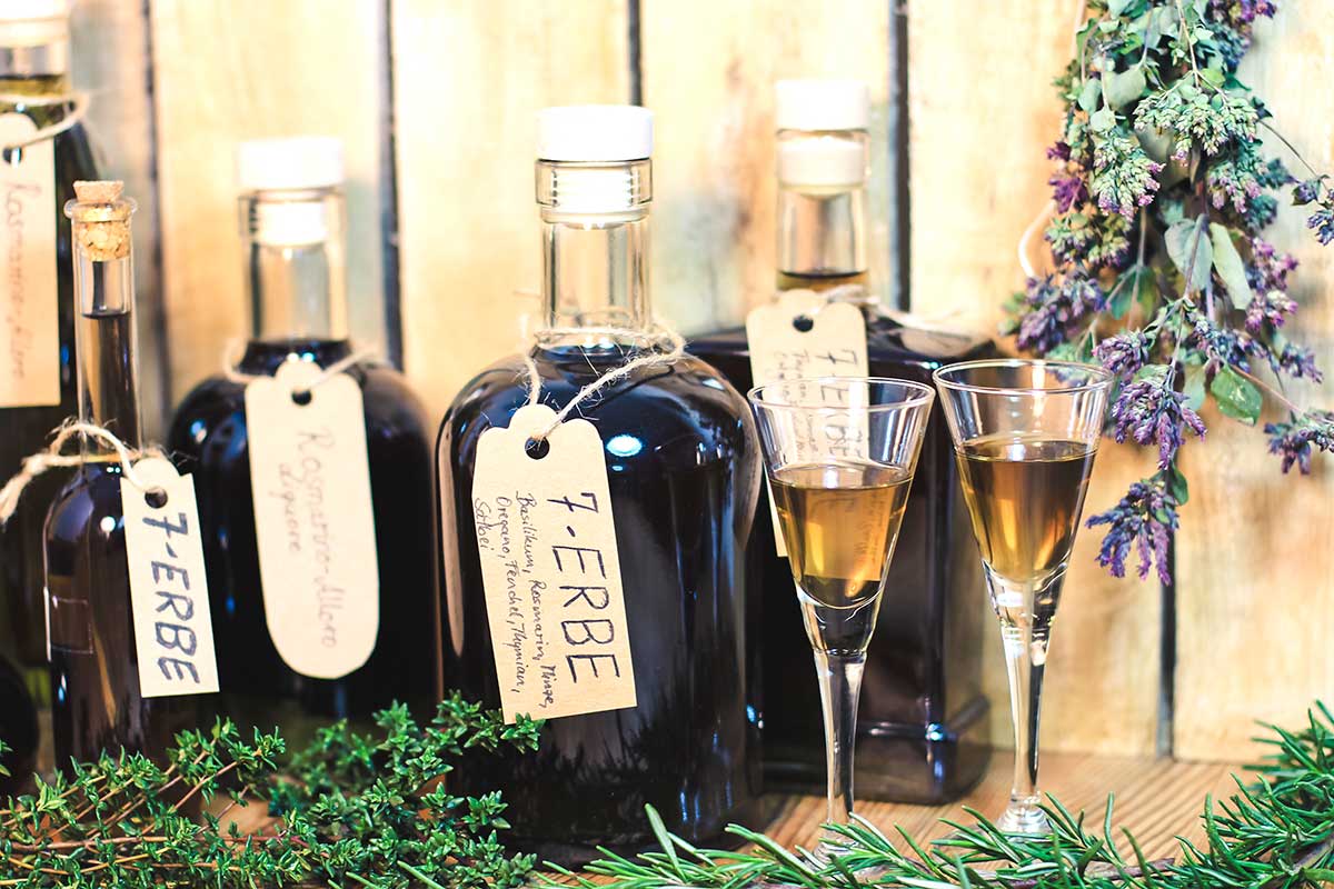Foto von mehreren Flaschen mit Kräuterlikör und zwei Gläsern mit Likör.