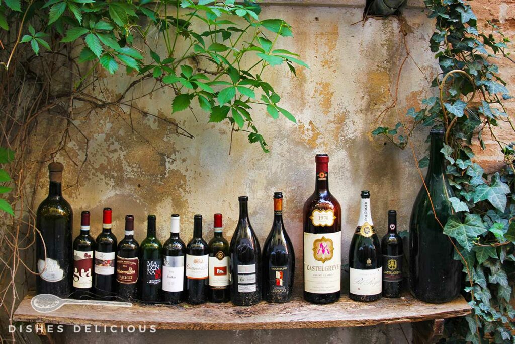 Foto von mehreren leeren Weinflaschen, die auf einem Holzbrett aufgereiht sind.