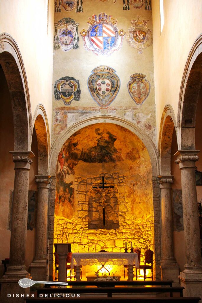 Foto vom Kirchenschiff von Santa Maria e San Rocco, an der oberen Wand sind Wappen aufgemalt, darunter steht der Altar.