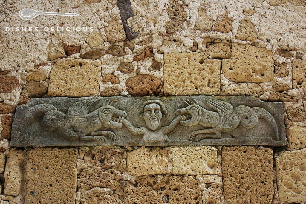 Foto eines steinernen und verzierten Querbalkens aus dem Mittelalter in der Fassade der Kirche Santa Maria e San Rocco.