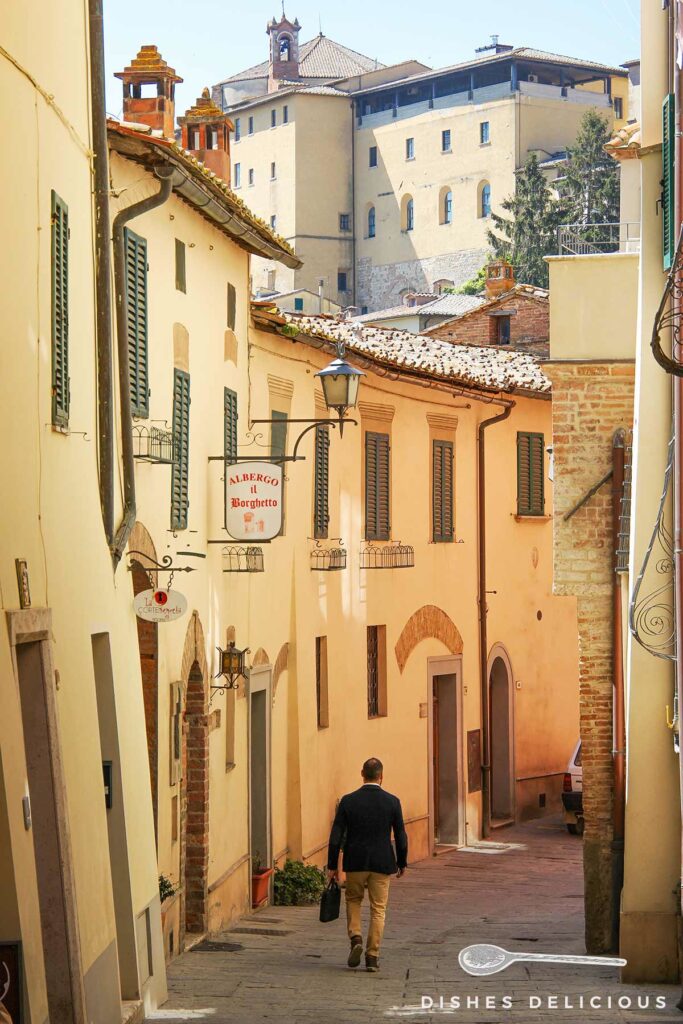 Foto einer Gasse in Montepulciano, im Hintergrund erhebt sich die Parrocchia del Santissimo Nome di Gesù.