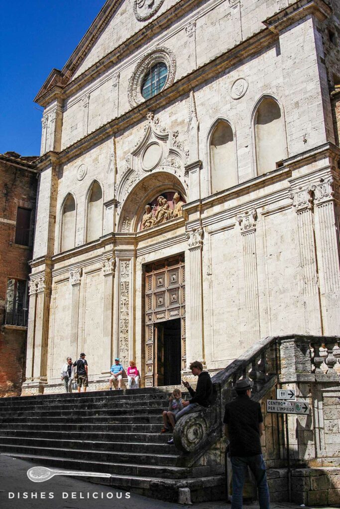 Foto der Sant'Agostino-Kirche von außen. Vor der Kirche stehen und sitzen Menschen.