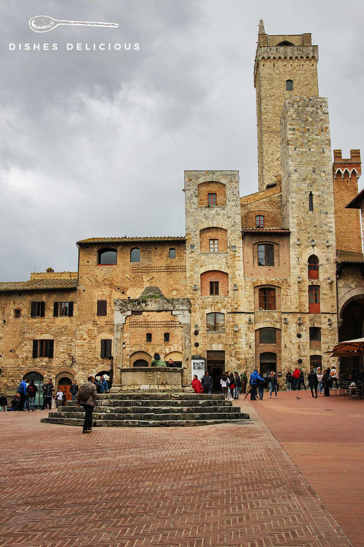 Foto der Piazza della Cisterna mit den zwei Türmen Torri degli Ardinghelli und einem Brunnen.