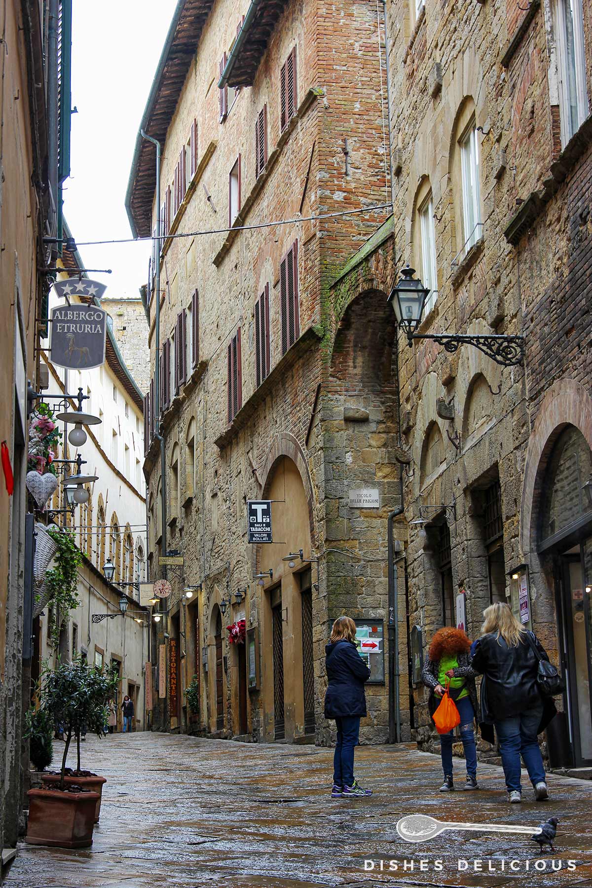 Foto einer Straße in Volterra mit hohen Palazzi aus dunklem Stein.