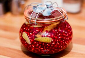 Foto von einem Einmachglas mit Granatapfelkernen, die in Weingeist ziehen.