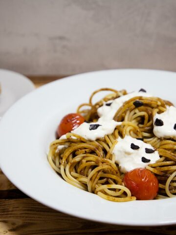 Ein Teller Spaghetti mit schwarzem Knoblauch, Tomaten und Burrata