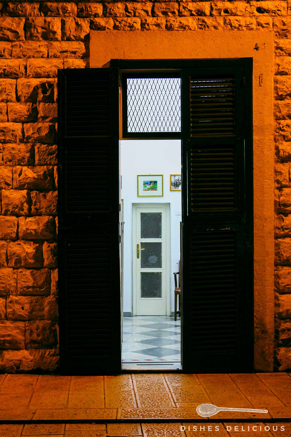 Eine offene Tür eines Hauses am Abend, die zu einer weiteren Tür führt.