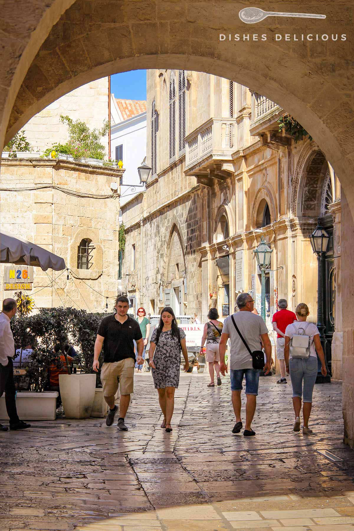 Stadttor zur Altstadt von Polignano a Mare, Menschen laufen eine Gasse entlang.