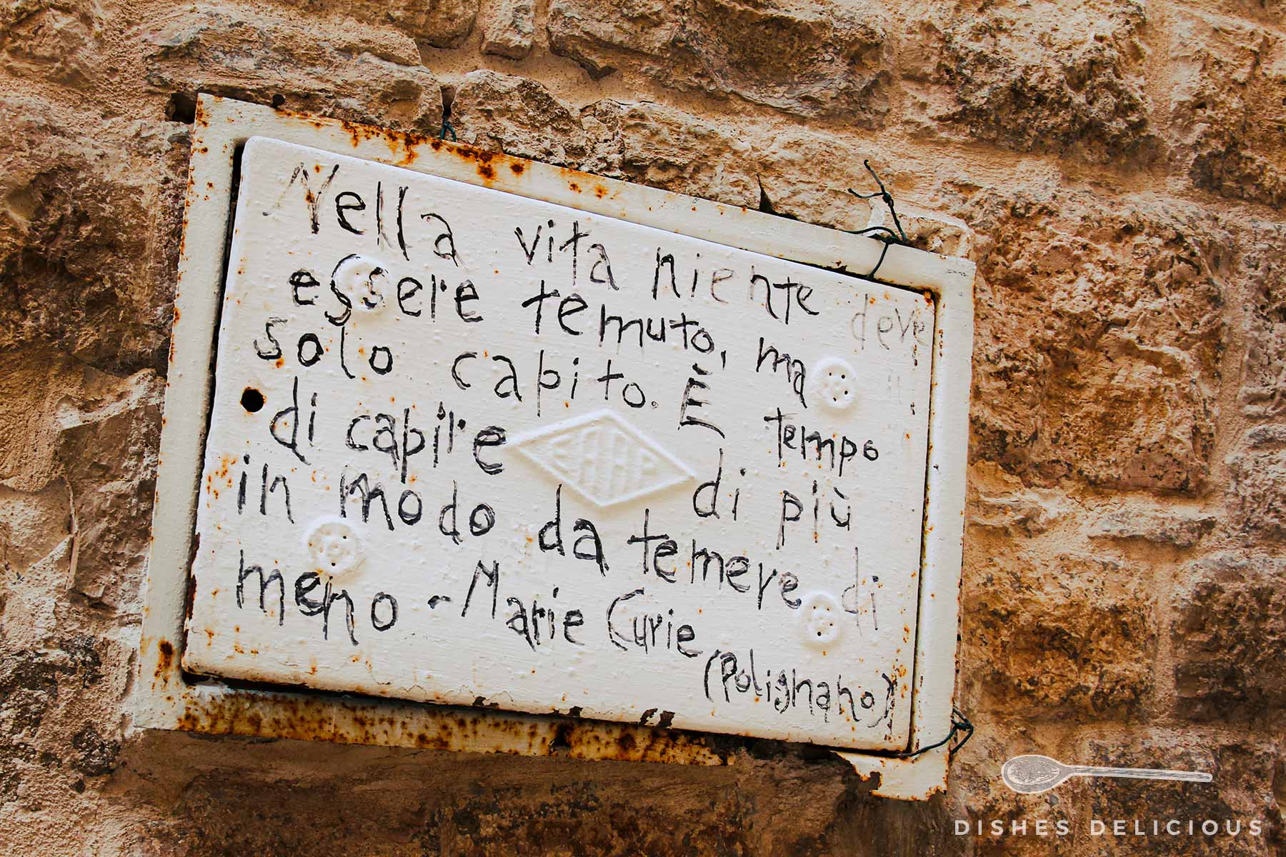 Eine mit einem Zitat von Marie Curie beschriftete Mauer in Polignano a Mare.