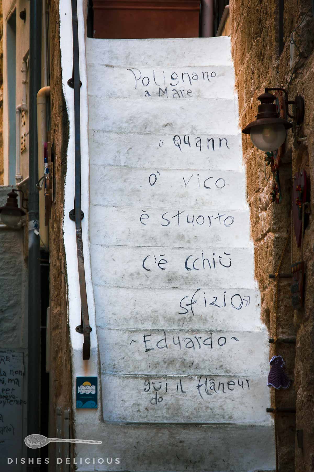 Mit einem Spruch beschriftete Treppenstufen in der Altstadt von Polignano a Mare.