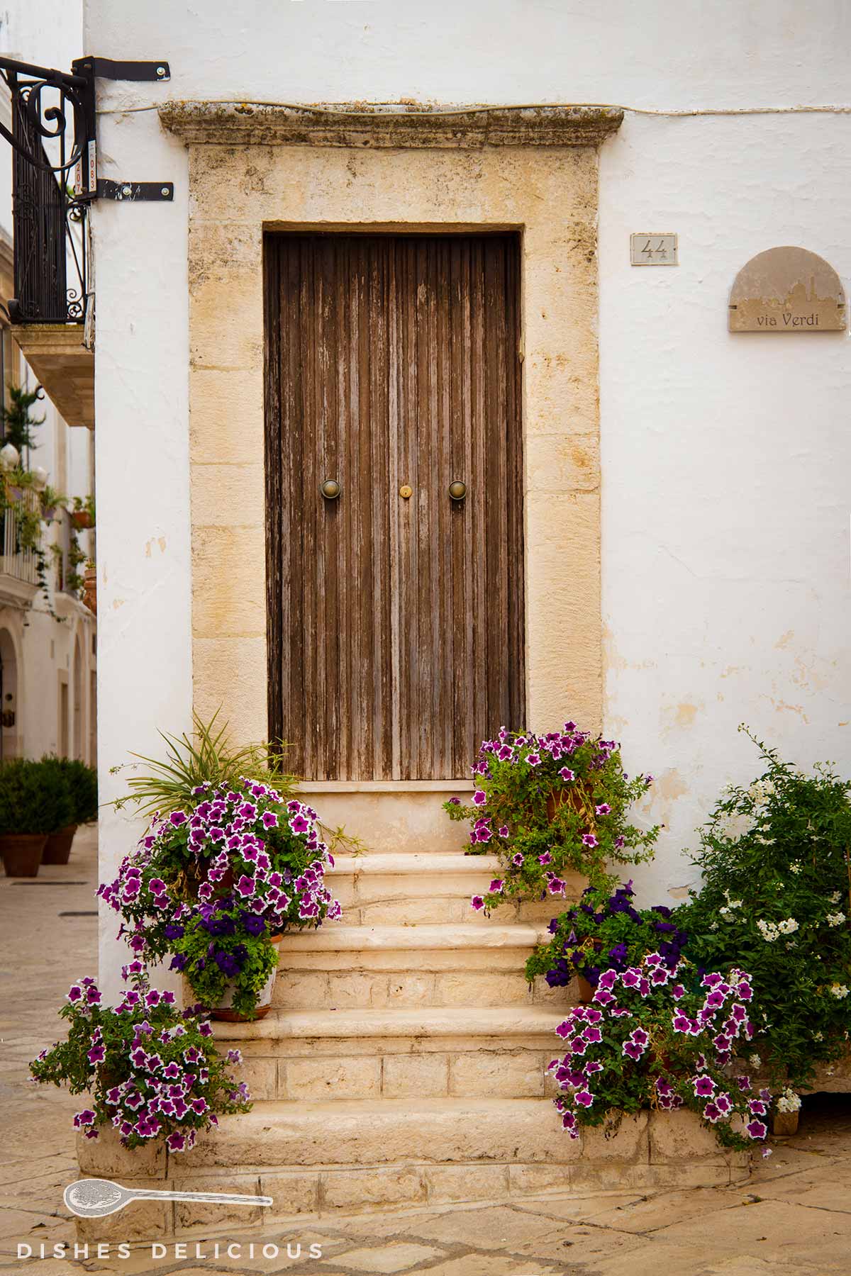 Ein Blumengeschmückter Hauseingang mit Treppenaufgang und Holztür.