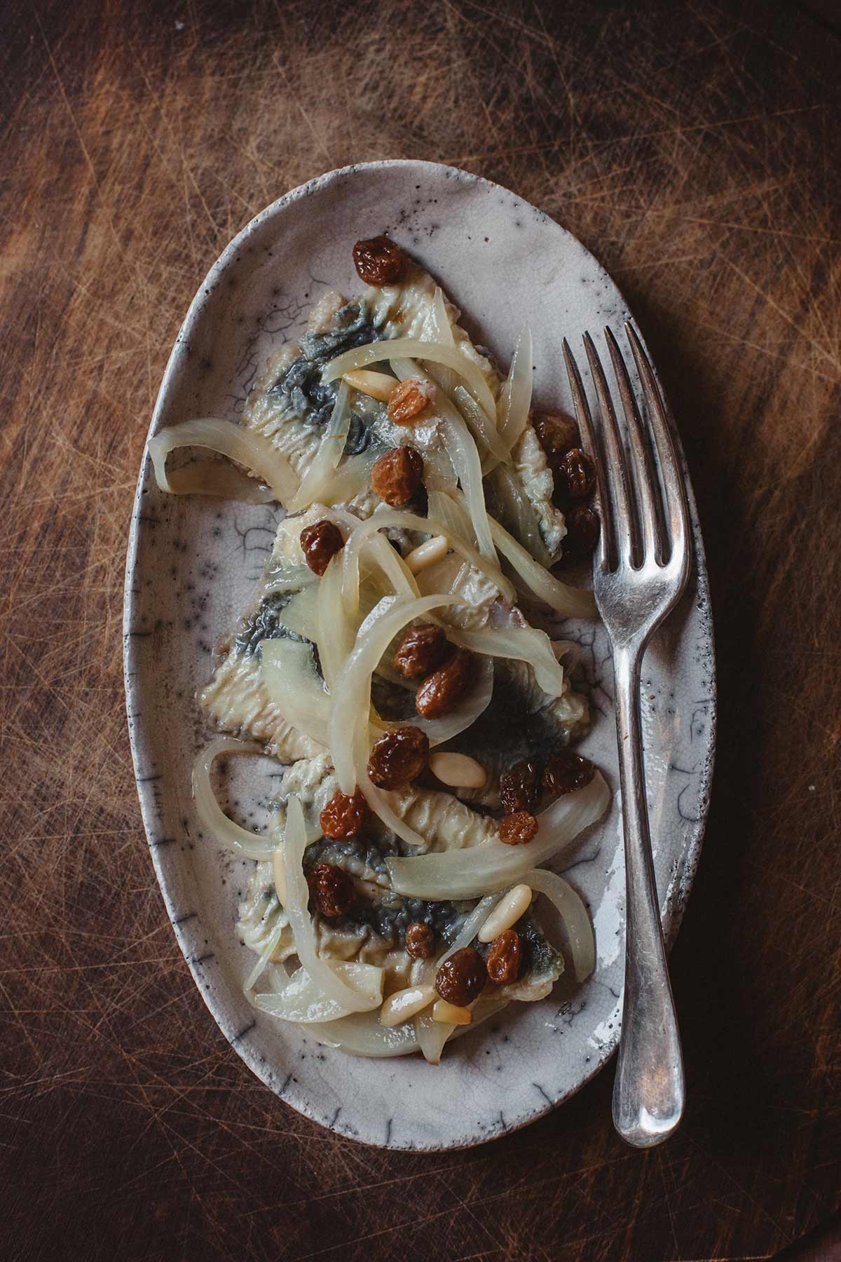 Klassische Cicchetti sind eingelegte Sardinen mit Zwiebeln, angerichtet auf einem Teller.