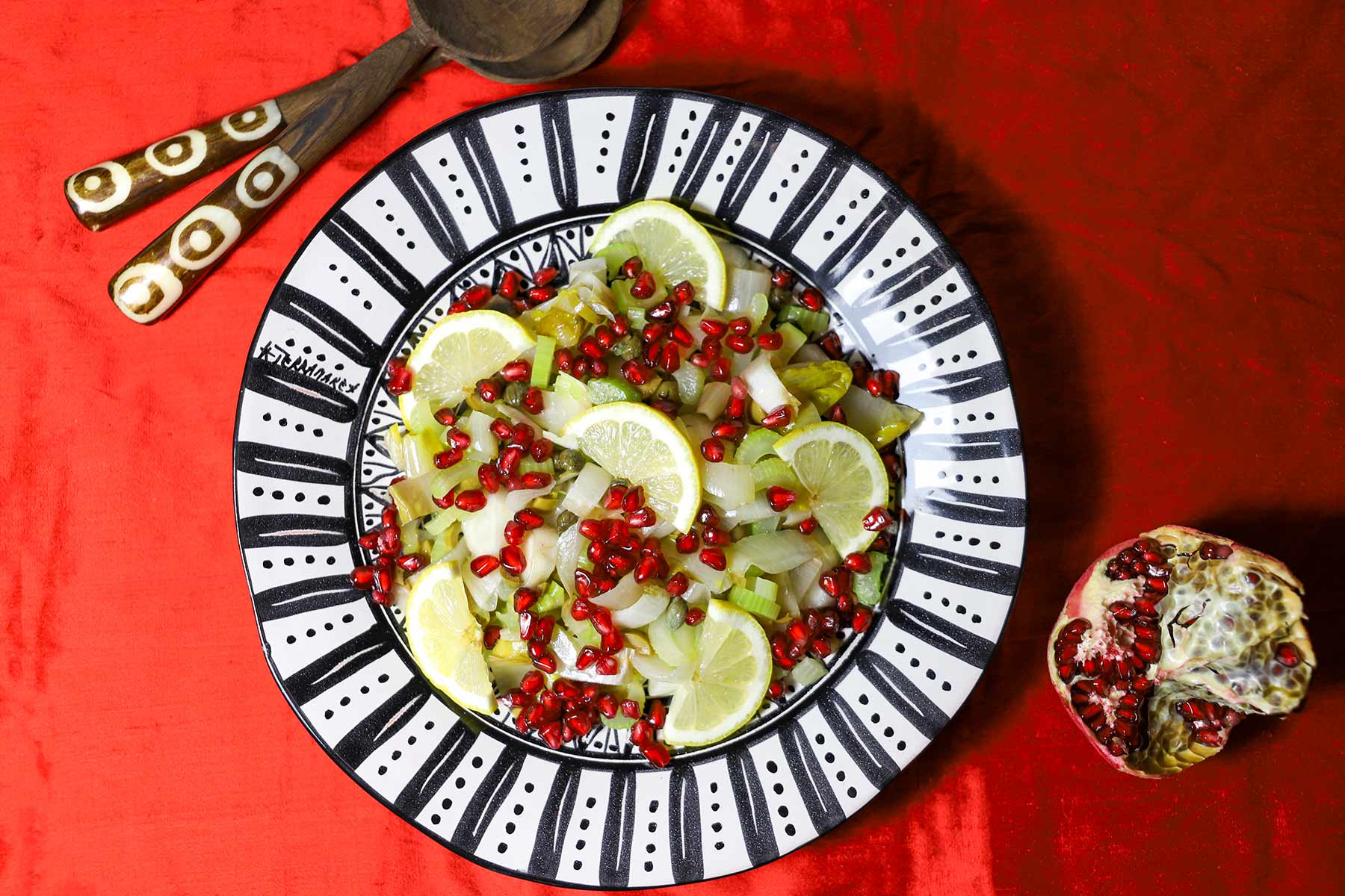 Ein Teller mit einem Salat aus Chicorée, Zitronenscheiben, Granatapfelkernen.