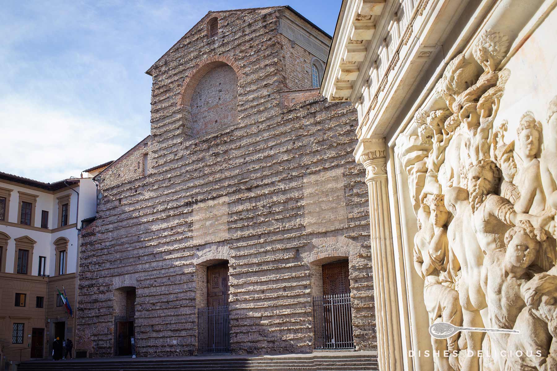 Schmucklose Fassade der San Lorenzo-Basilica, im Vordergrund Verzierungen eines Statuensockels.