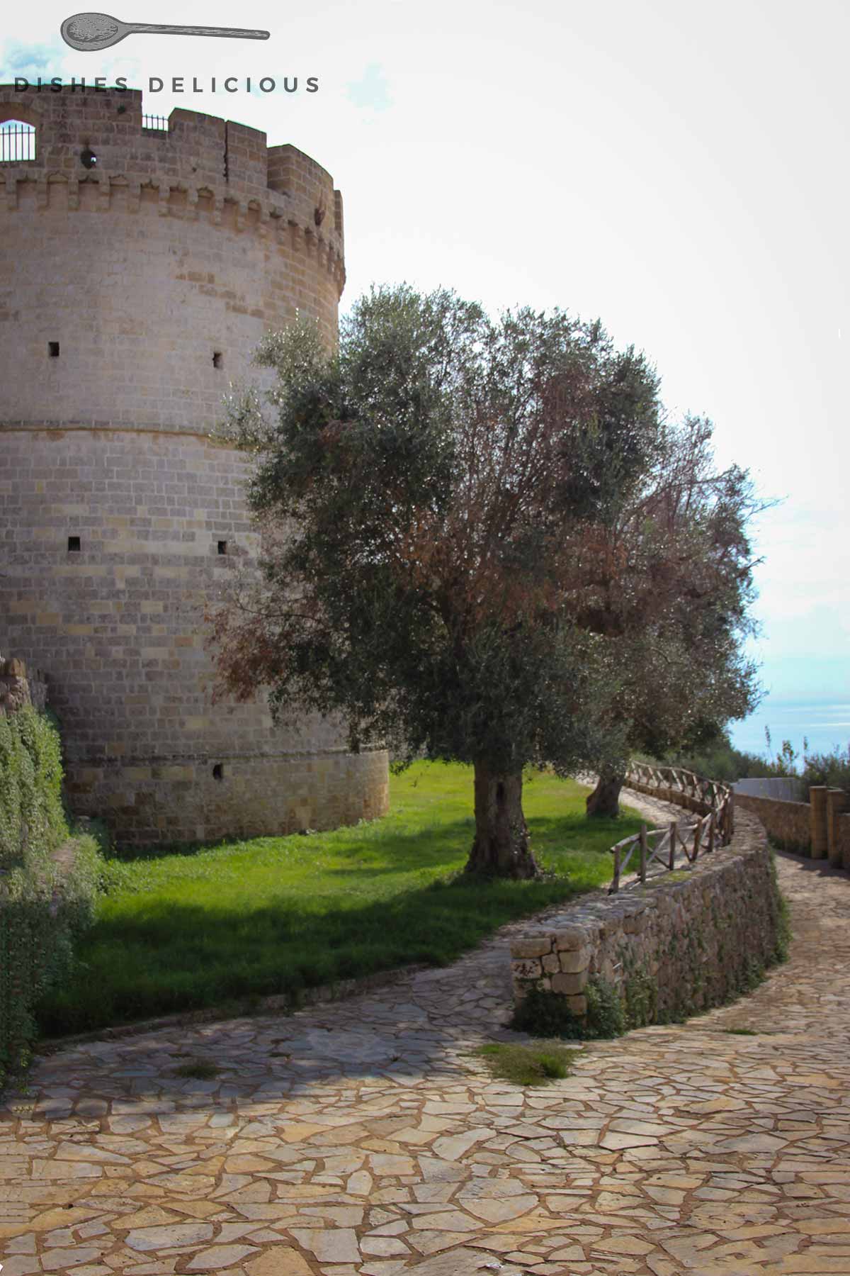 Der wuchtige Wachturm der Aragonier-Burg, an dem ein kleiner Spazierweg entlangführt.