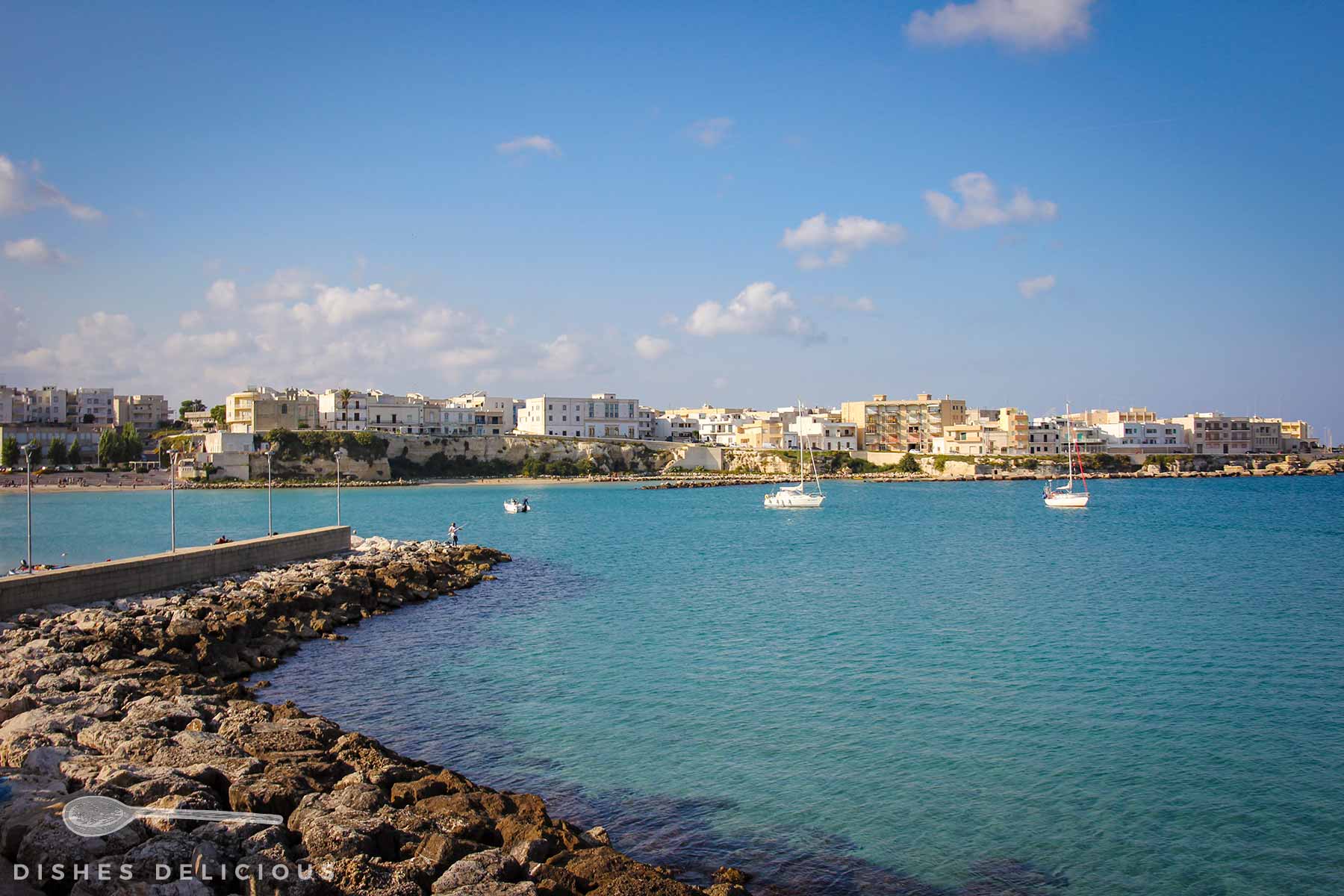 Bucht von Otranto, kleine Boote ankern auf dem Wasser, im Hintergrund einer der neuen Ortsteile.